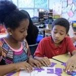 Two students work together at a desk in a clasroom