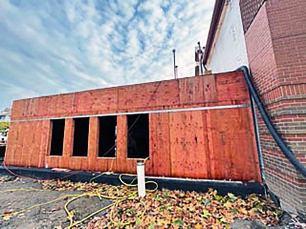 a one story building addition under construction is attached to a brick building