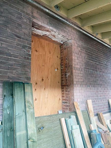 a concrete wall has a space for a window with plywood instead of glass