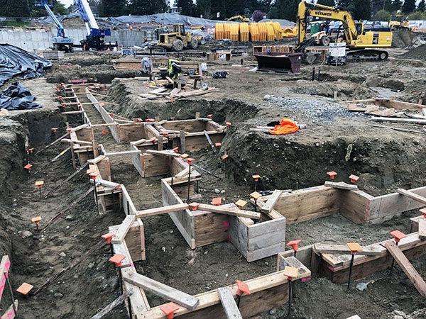 wooden formwork is in place in holes in the dirt of a construction site