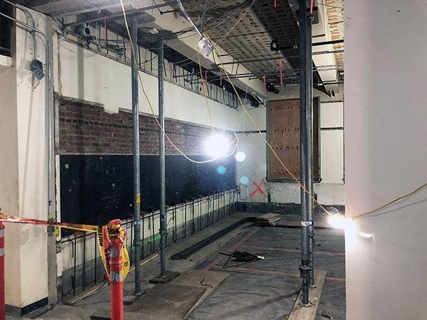 a room under construction with a blackboard below bricks, there is an x on one wall