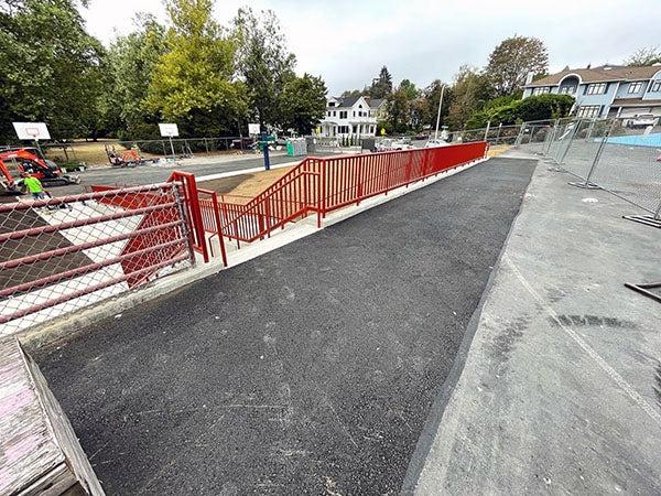 an asphalt area with a fence and stairs