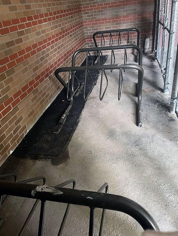 bike racks inside a fence by a brick building