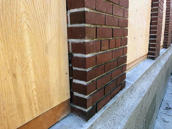 a close view of a brick section of wall with plywood window next to it