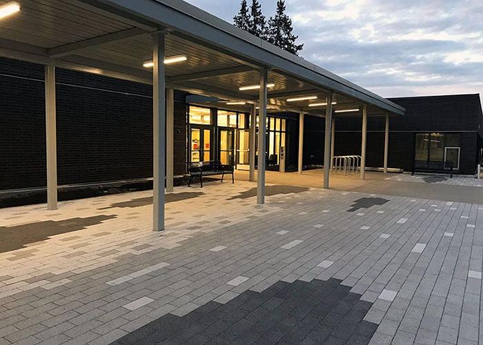 a breezeway in front of a building with glass doors and decorative pavers